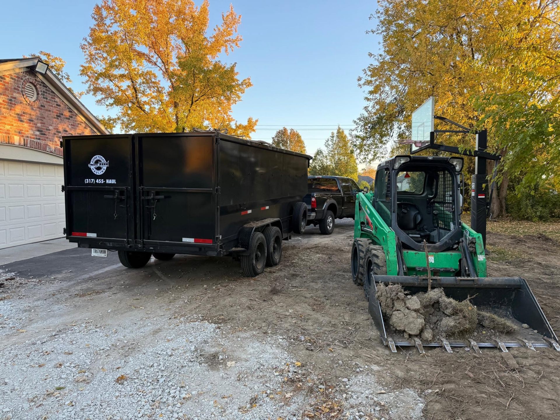 Gone Today Hauling Ram 3500 dually pickup with roll-off dumpster and skid steer on a Central Indiana job site